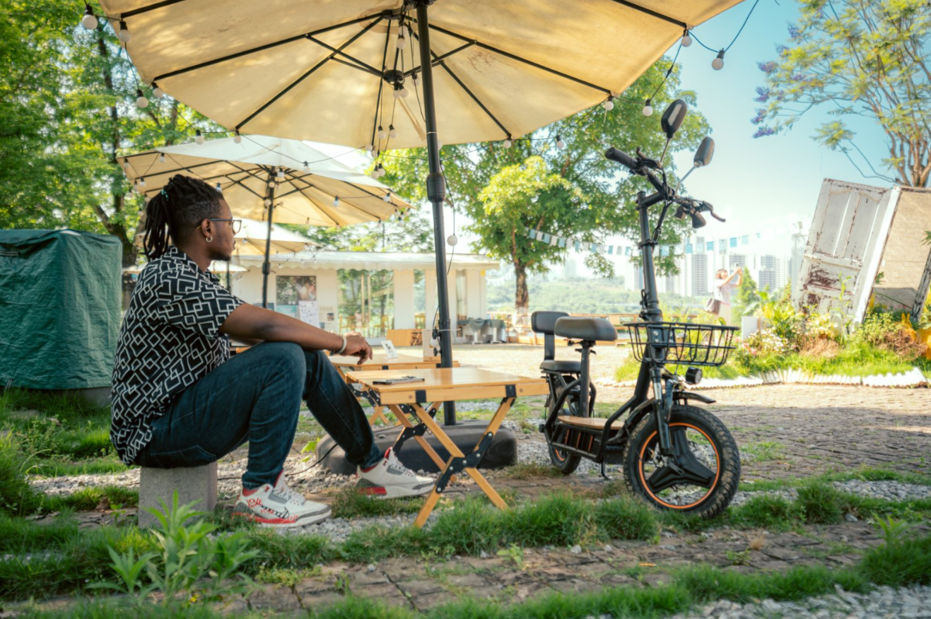 Kukirin C1 Pro electric bike parked outdoors near a man sitting at a cafe table